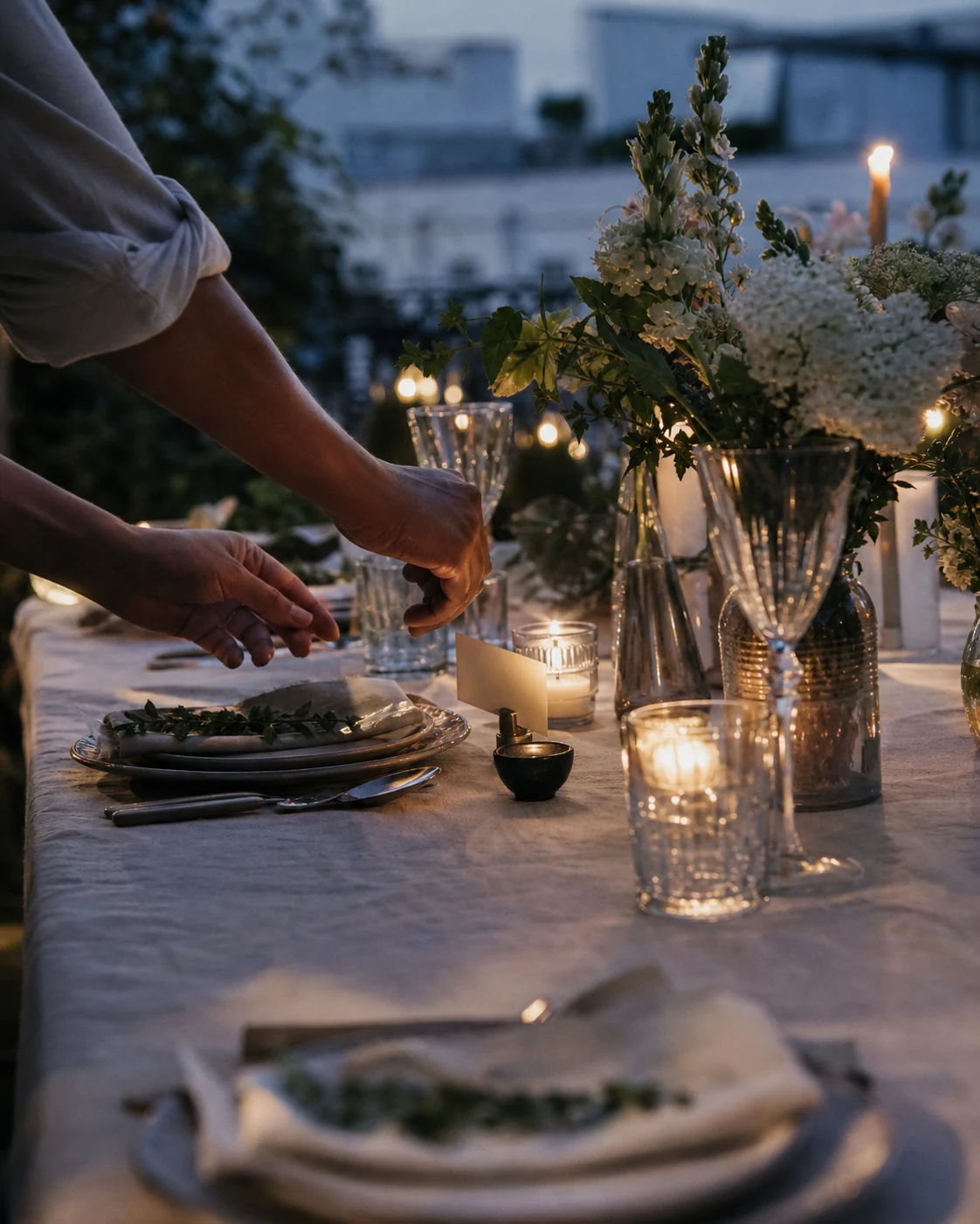 Hands placing the final details on a candlelit dinner table